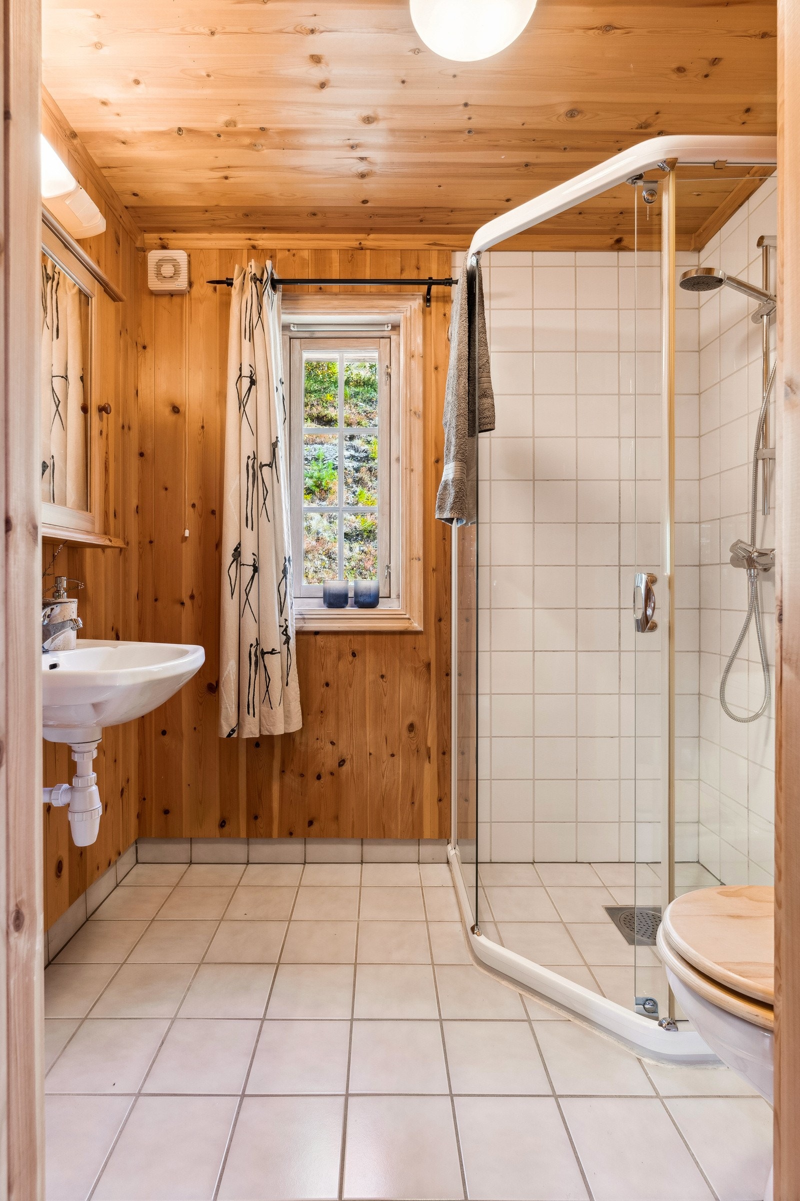 Begge badene har flislagt gulv med varme, flislagt dusjsone og panel på vegger og i himling. Galleribilde