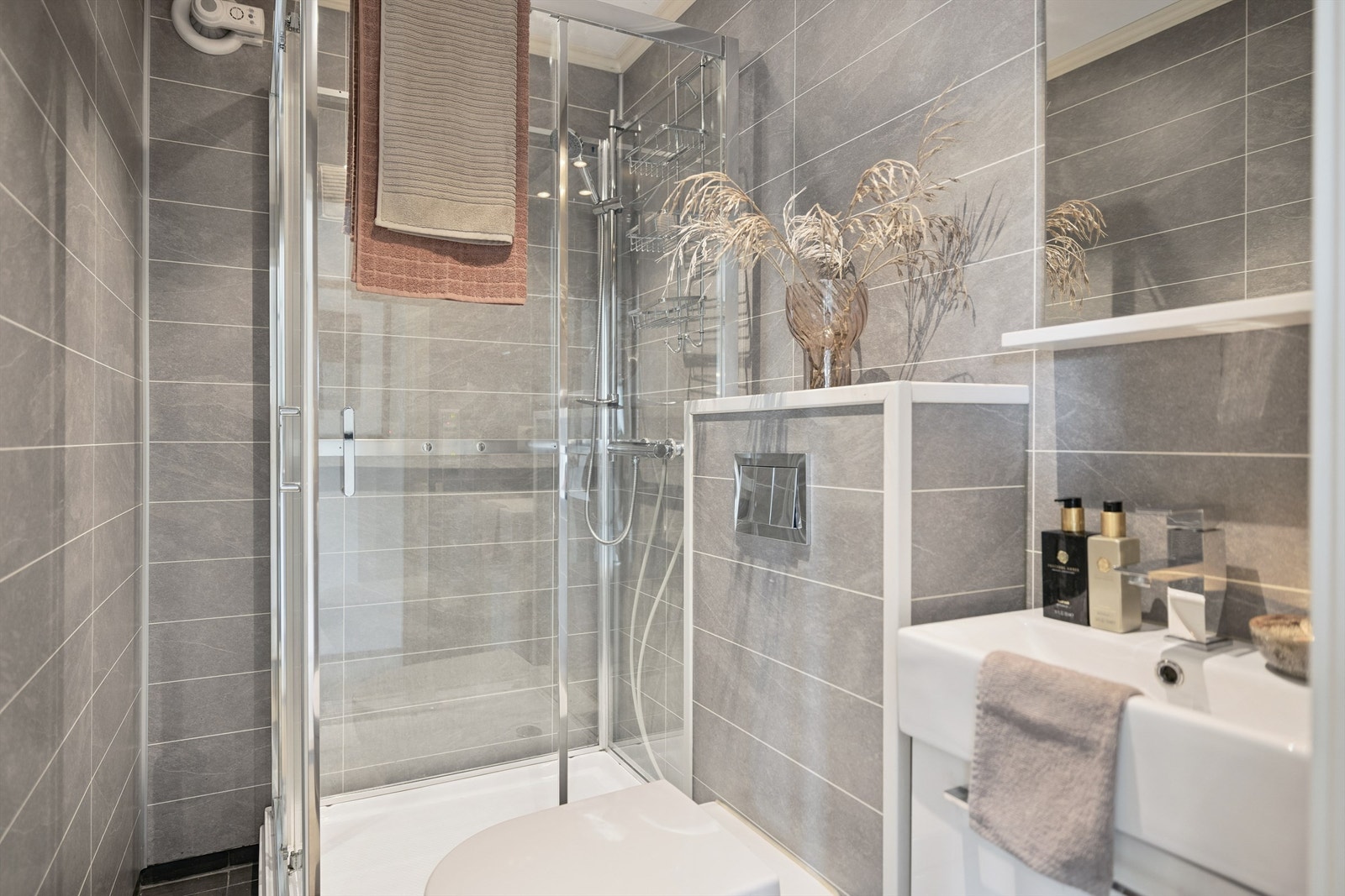 Rommet er utstyrt med dusjkabinett, vegghengt toalett og en moderne servantinnredning. Galleribilde