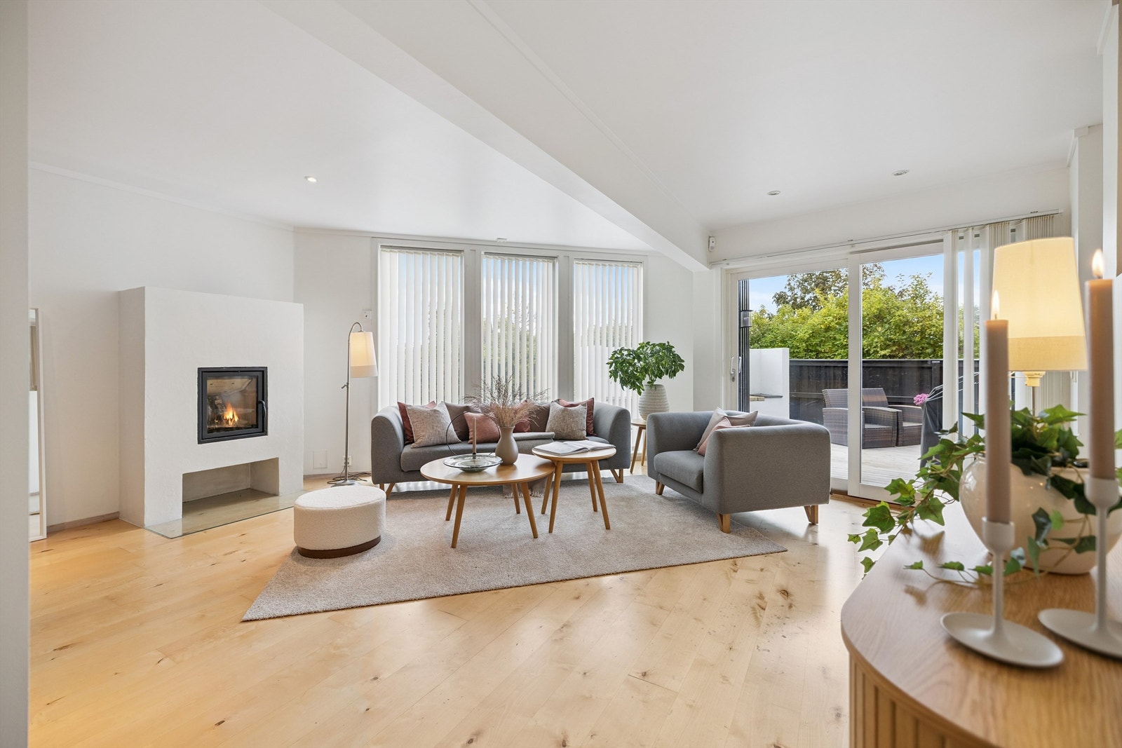 Fra entréen ledes du inn i en lys og romslig stue med en moderne peisinnsats fra Nordpeis. Galleribilde