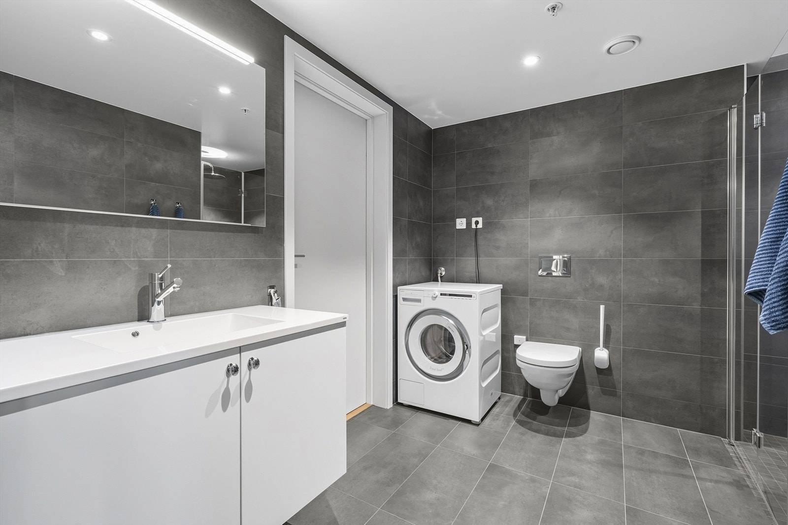 Badet inneholder servant i innredning, vegghengt wc, dusjnisje og opplegg til vaskemaskin Galleribilde