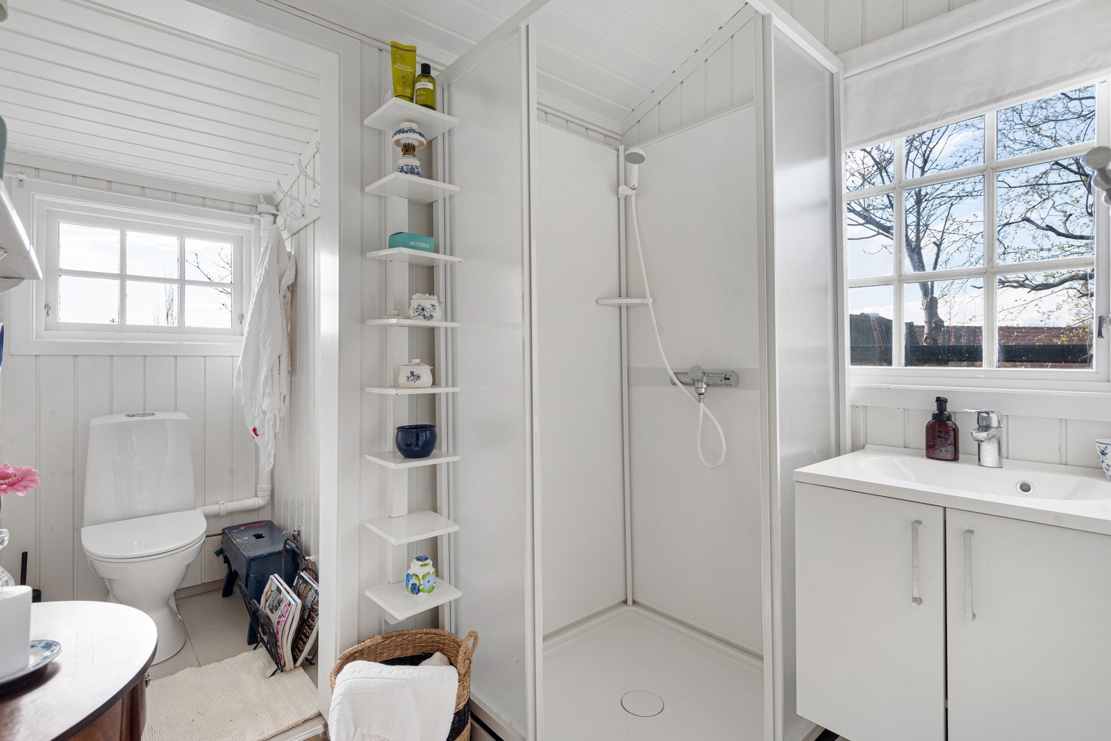 På badet det hvitmalt panel på veggene og det er lagt store, lyse fliser på gulvet. Galleribilde