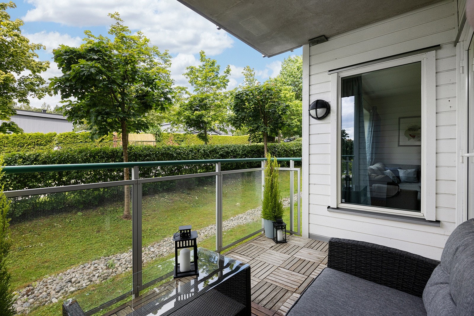 Nord-nordvestvendt balkong på ca. 6,5m² med tretremmer på betongdekke og malt liggende kledning. Rekkverk i glass i alu.-profiler. Galleribilde
