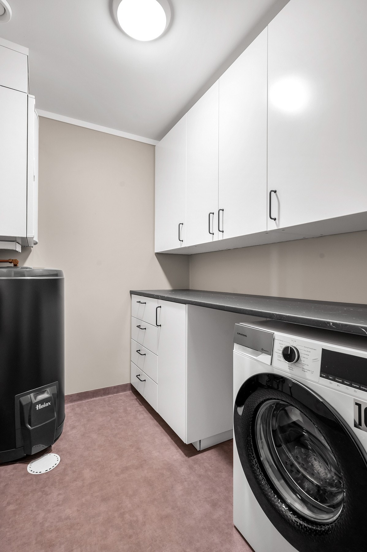 Innredet vaskerom med benk, overskap, opplegg for vask/tørk, varmtvannsbereder og balansert ventilasjon. Galleribilde