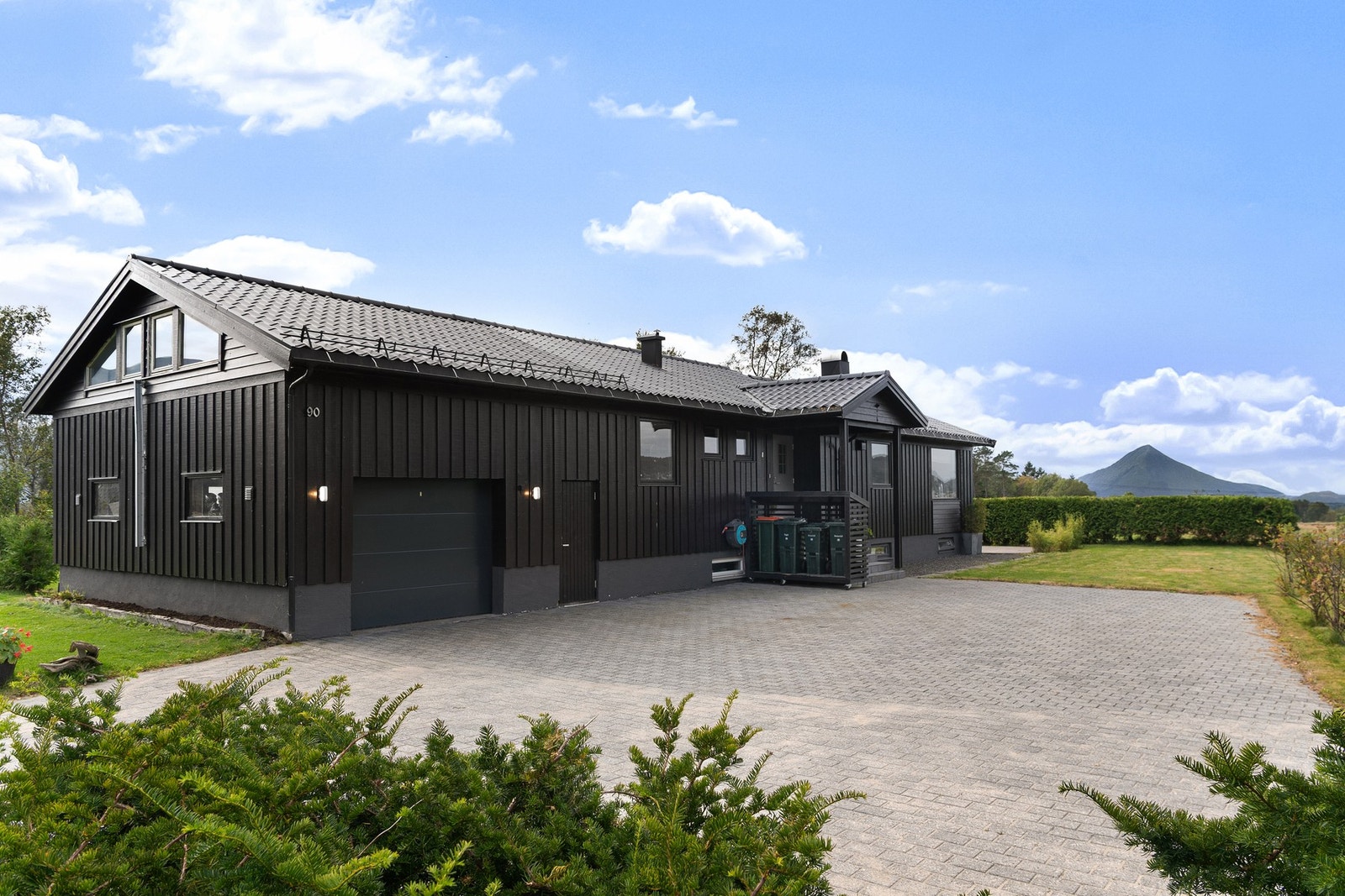 Romslig brosteinsbelagt gårdsplass med plass til flere biler. I 1989 fikk boligen ett tilbygg bestående av garasje og innredet loft med tilgang fra boligen. Galleribilde