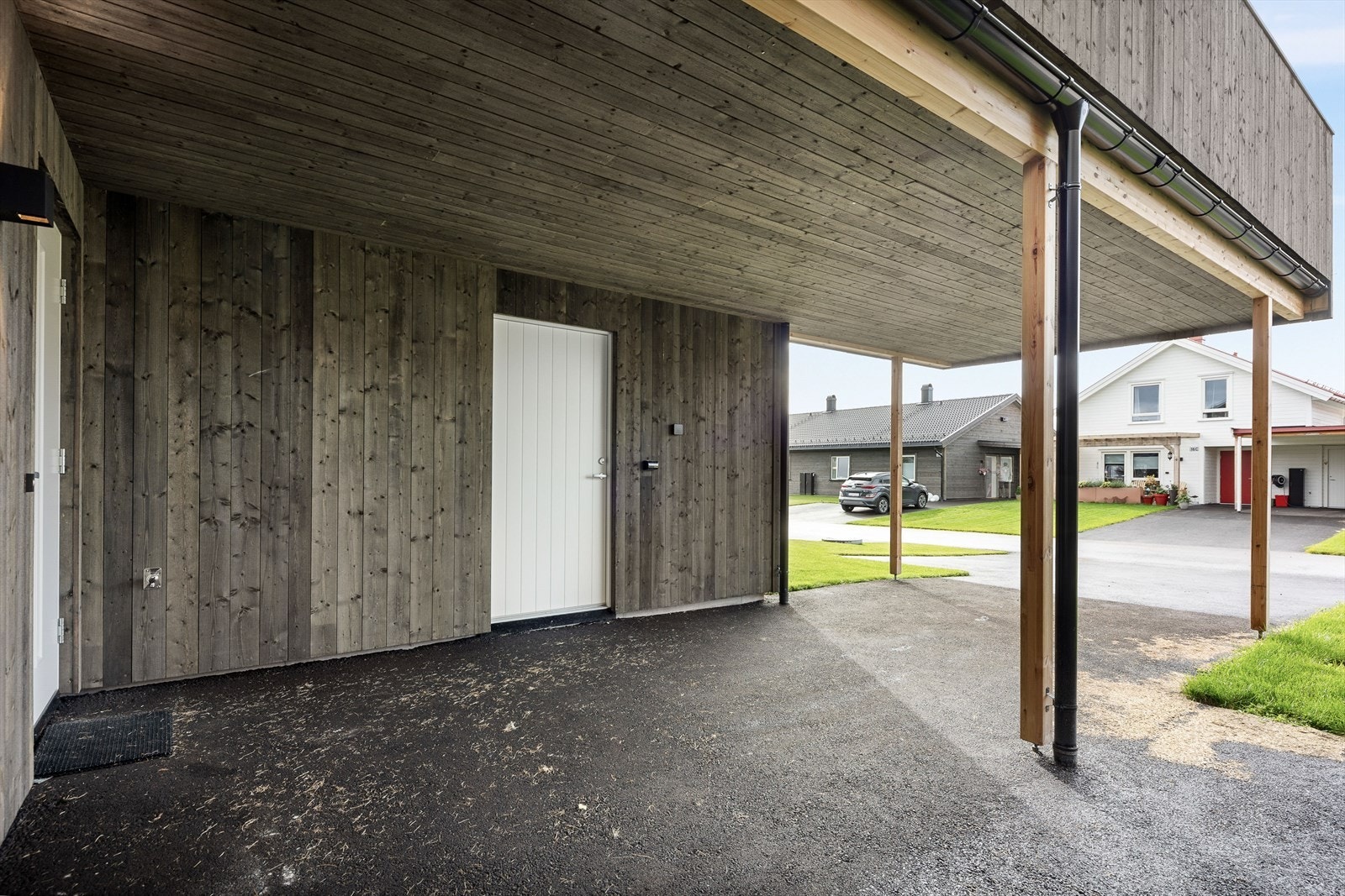 Inngangsparti med carport, bod og en biloppstillingsplass i innkjørselen Galleribilde