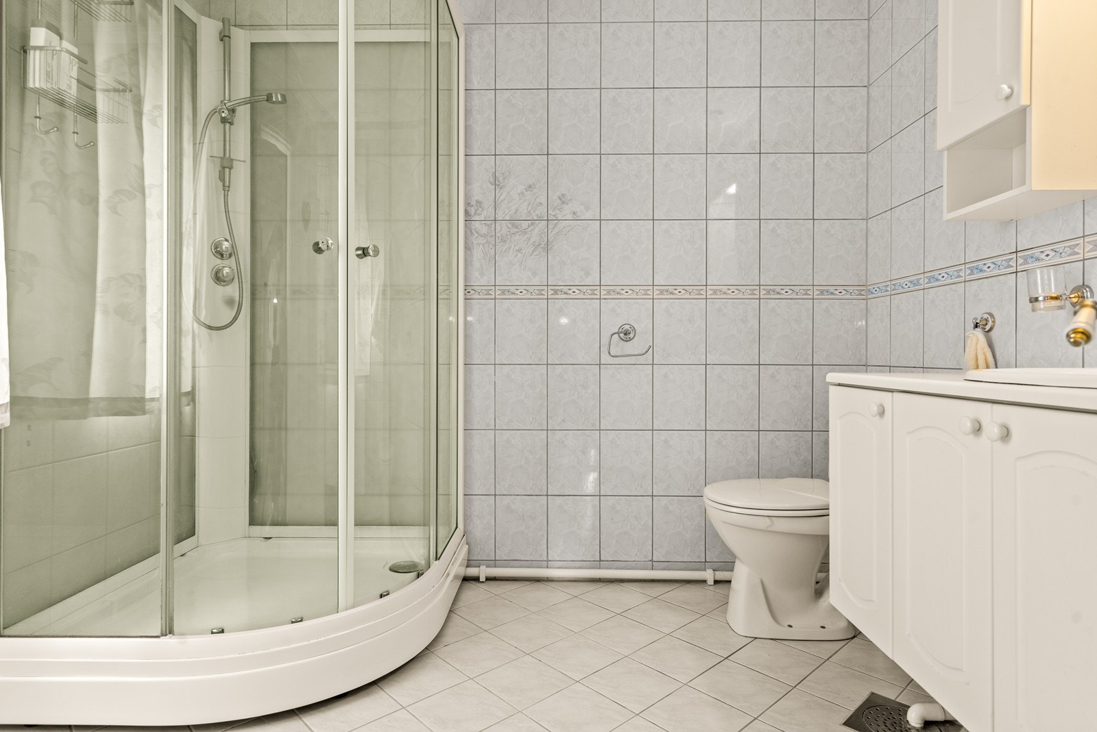 Flislagt bad med toalett, servantinnredning og dusjkabinett. Galleribilde