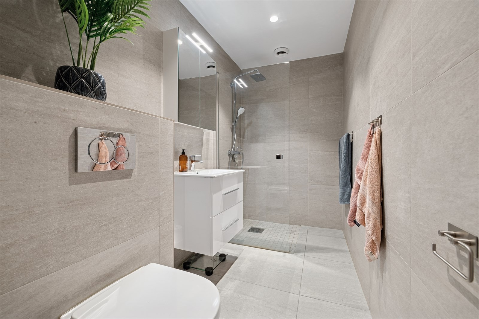 Pent bad fra 2023 med varmekabler, vegghengt toalett og dusjhjørne. Et eget rom i samme etasje brukes som vaskerom. Galleribilde