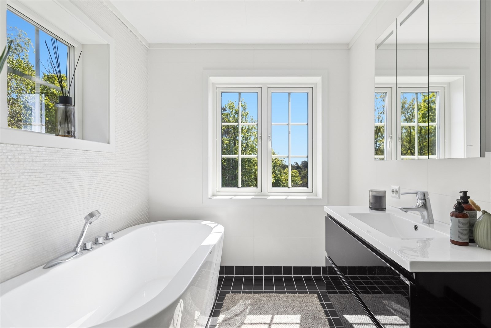 Lekkert bad med moderne servantinnredning, speilskap og store vindusflater som gir flott lysinnslipp og utsyn mot grønne omgivelser. Galleribilde