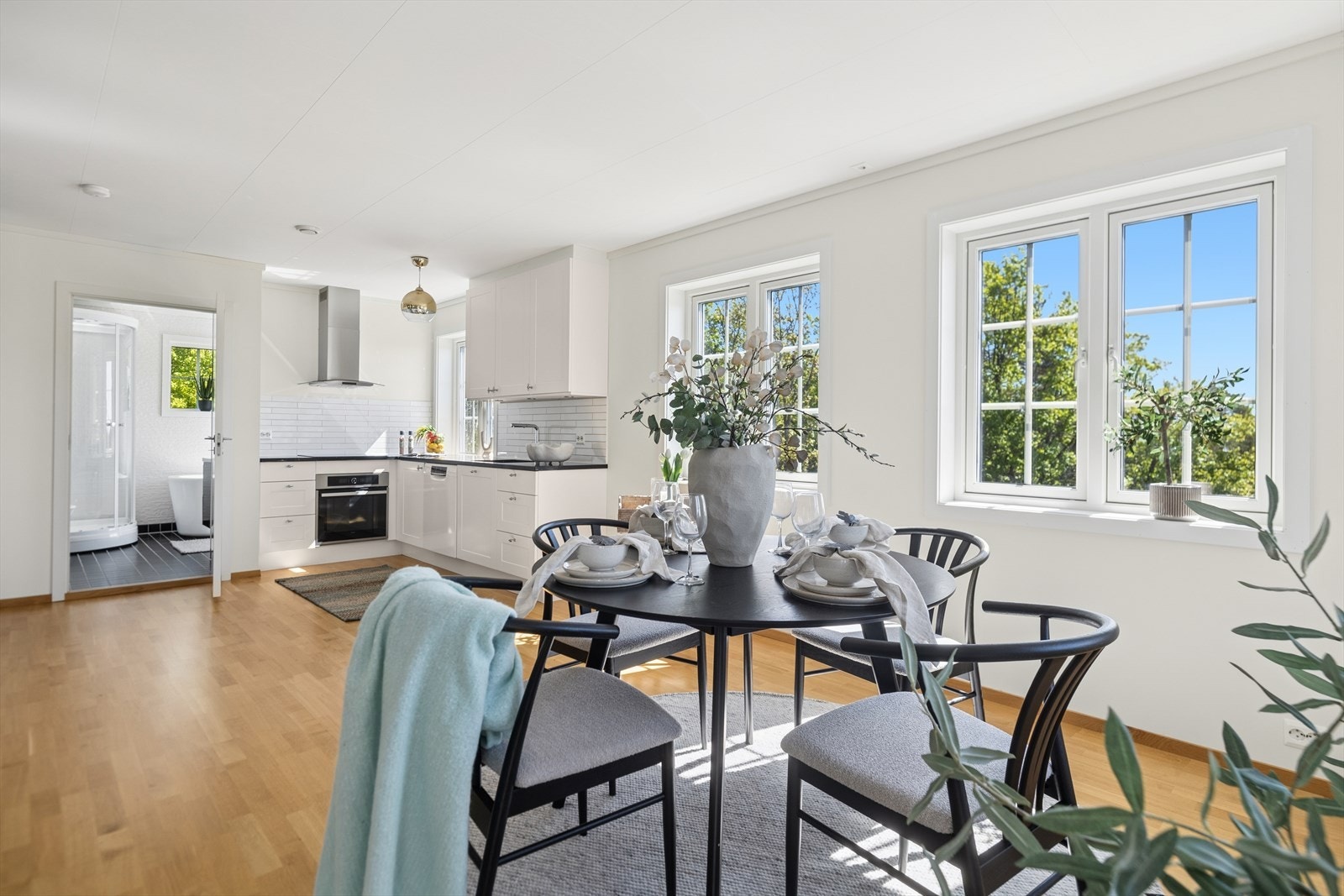 Åpen og sosial sone mellom stue, kjøkken og spisestue. Store vindusflater slipper inn rikelig med dagslys og gir utsyn mot grøntarealer. Praktisk adkomst til bad. Galleribilde