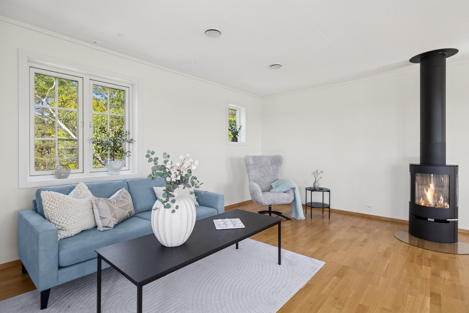 Stue med innbydende sofakrok, peisovn og store vinduer. Her får du en lun og koselig atmosfære med grønne omgivelser tett på..jpg Galleribilde