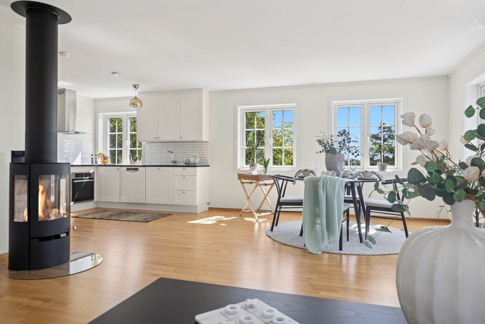 Rommet sett mot kjøkkenet og peisovnen. Her vises hvordan kjøkken og stue henger naturlig sammen i en gjennomført planløsning..jpg Galleribilde