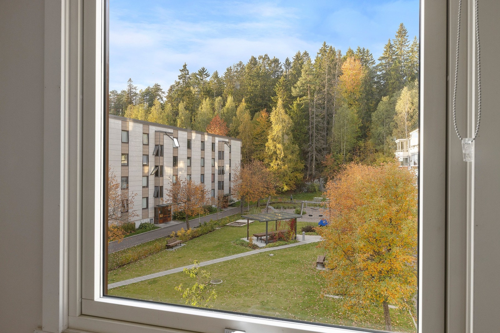 Rommet vender seg ut mot grønne og rolige omgivelser, med utsikt over borettslagets fellesområde. Galleribilde