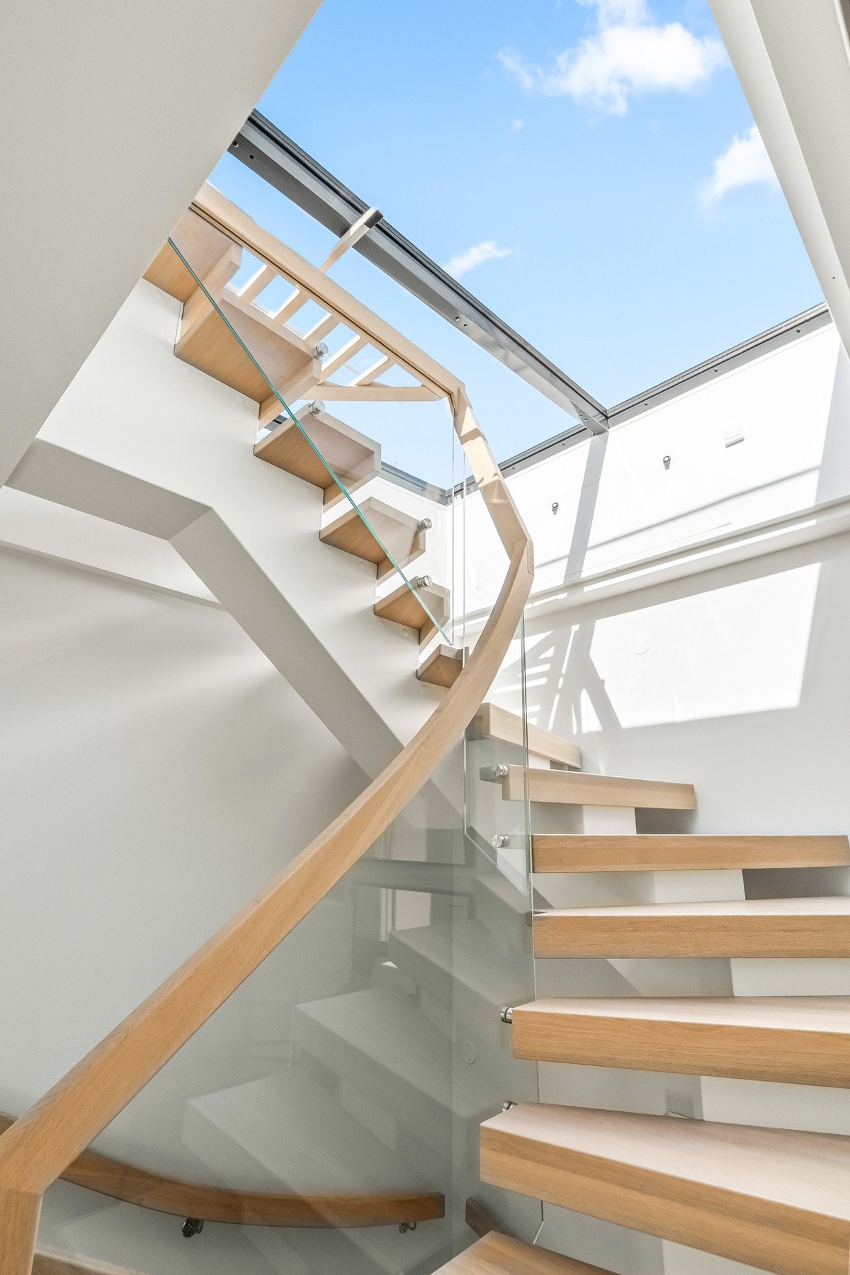 Stilren trapp med eiketrinn og glassrekkverk leder opp til boligens takterrasse.