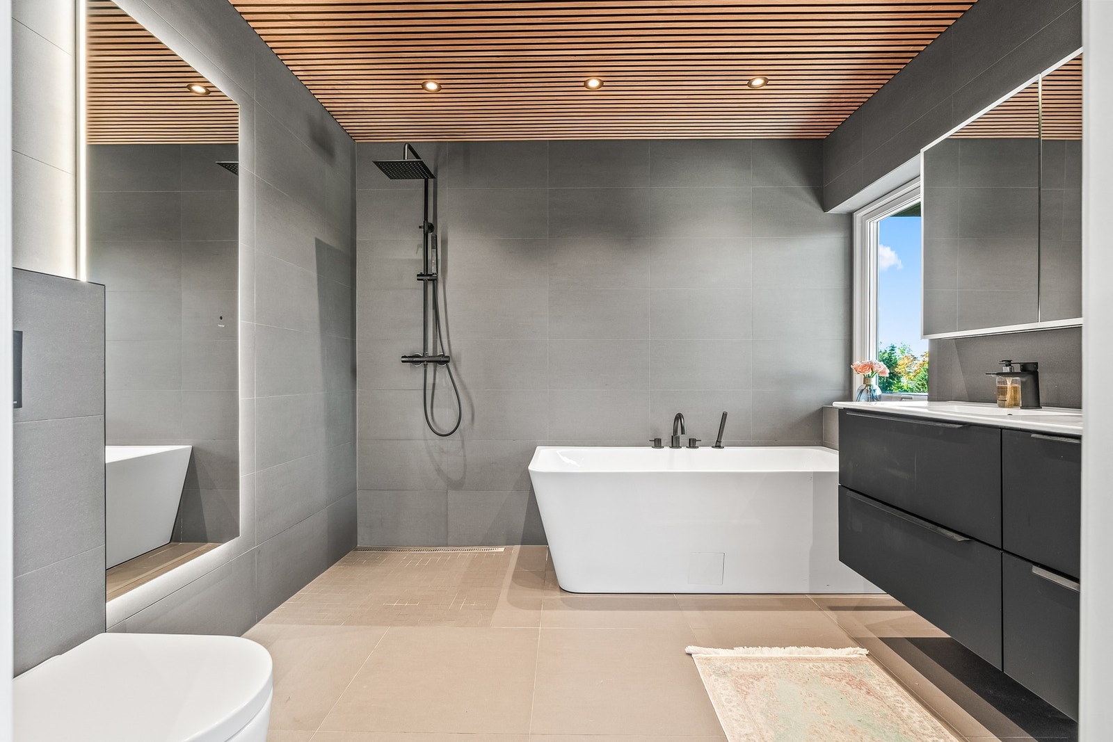 Eget bad i andre etasje med regnfallsdusj og moderne fliser.