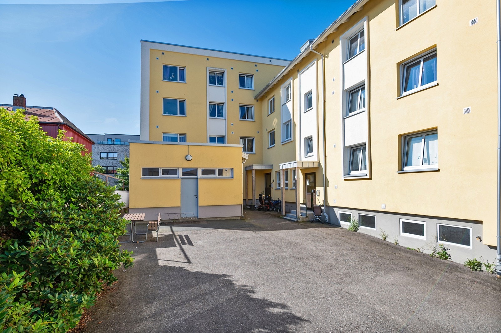 Eiendommen har inngjerdet, asfaltert bakgård med rhododendronbed, sittebenker og overbygde inngangspartier med porttelefon. Galleribilde