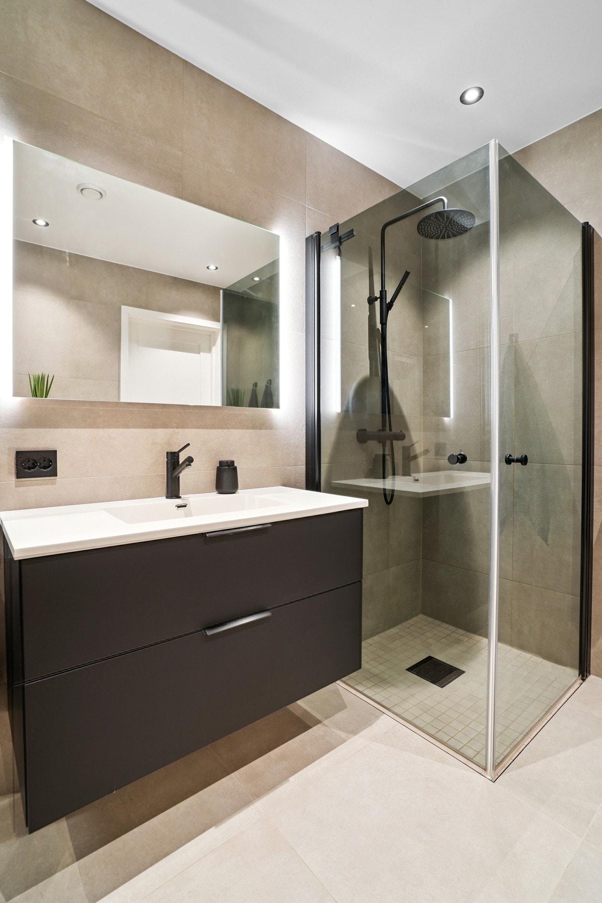 Innredet med servantinnredning med to mørke slette skuffer, helstøpt servant, speil med belysning bak - Galleribilde