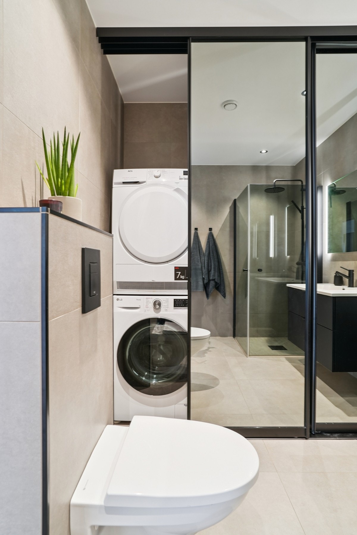 Gjennomtenkt bad med vaskeromsdel diskret gjemt bak elegante speilfronter - både praktisk og lekkert. Her er det opplegg for vaskemaskin og tørketrommel. Galleribilde