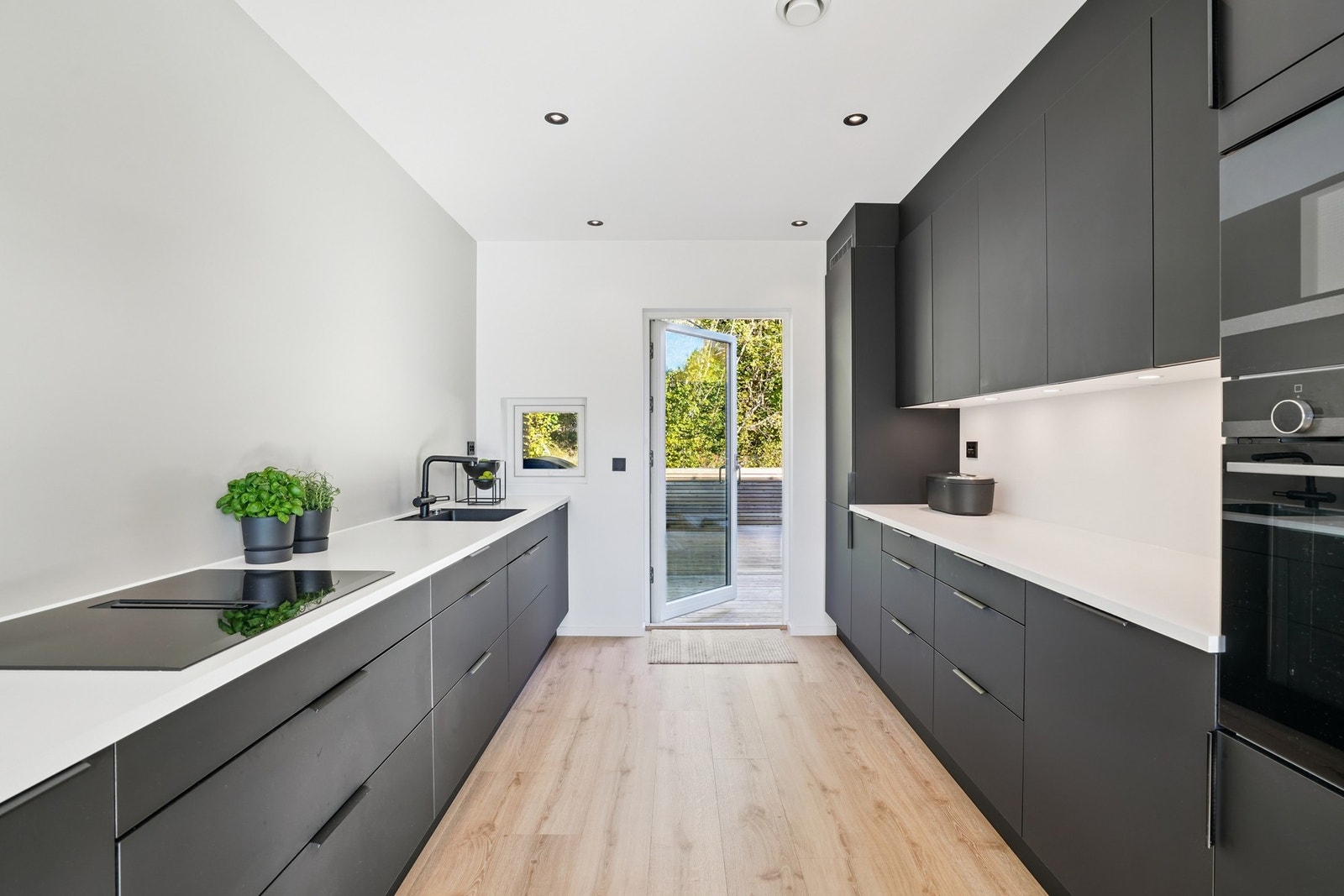 Lekker kjøkkeninnredning fra HTH med mørke glatte fronter og lys laminat benkeplate. Galleribilde