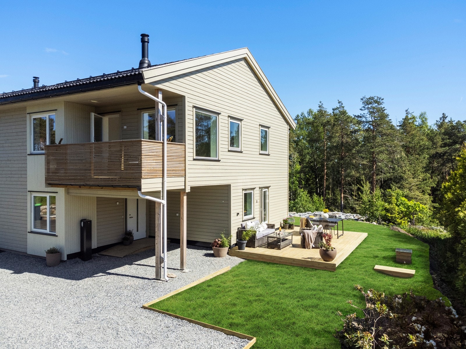 Gruslagt inngangsparti med parkering i carport og på stor gårdsplass (Det er retusjert inn grønn plen) Galleribilde