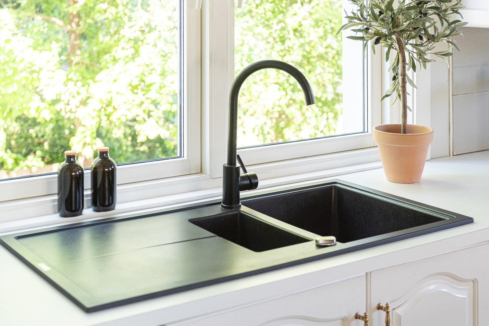 Kjøkkenvask med utsyn mot hagen og oversiktlig arbeidsflate. Galleribilde