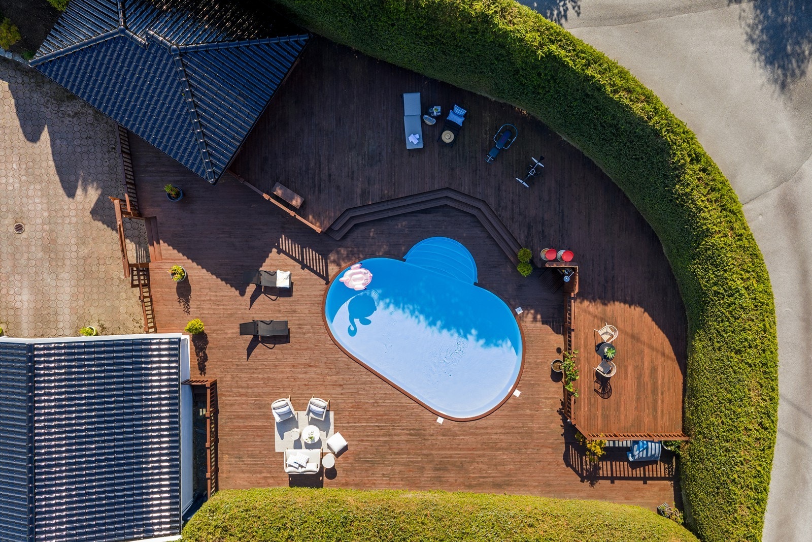 Stort basseng omkranset av stort terrasseområde og overbygget stue Galleribilde