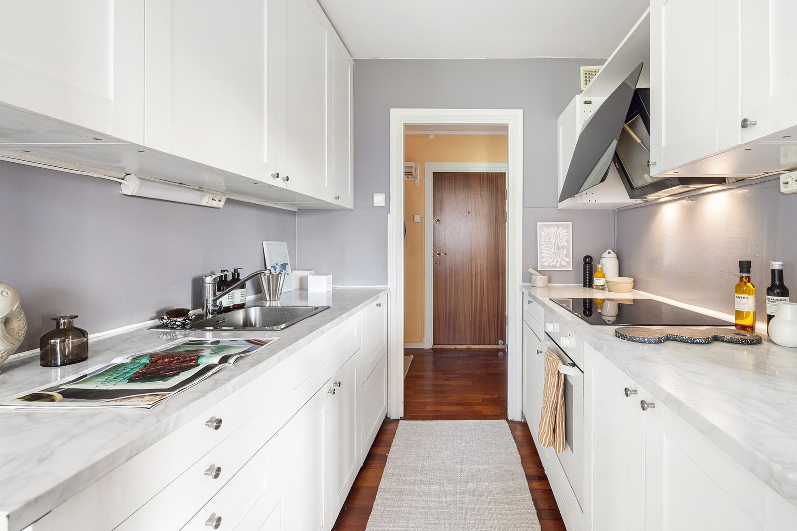 Innredning byr på hvite skapfronter, laminat benkeplater, nedfelt oppvaskkum og et greps armatur. Galleribilde