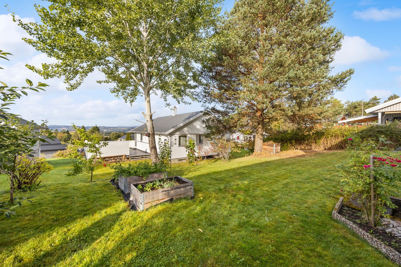 Tomten er pent opparbeidet med plen og beplantning. Galleribilde