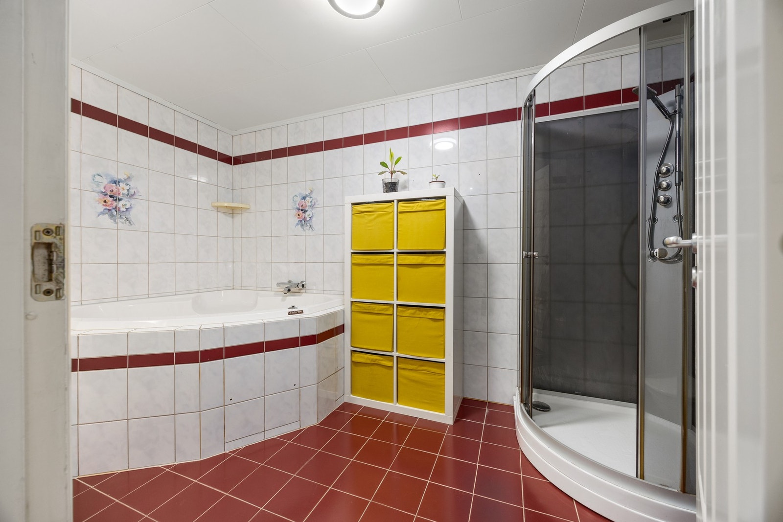 Romslig flislagt bad med gulvvarme, WC, servantskap, dusjkabinett og badekar. Galleribilde