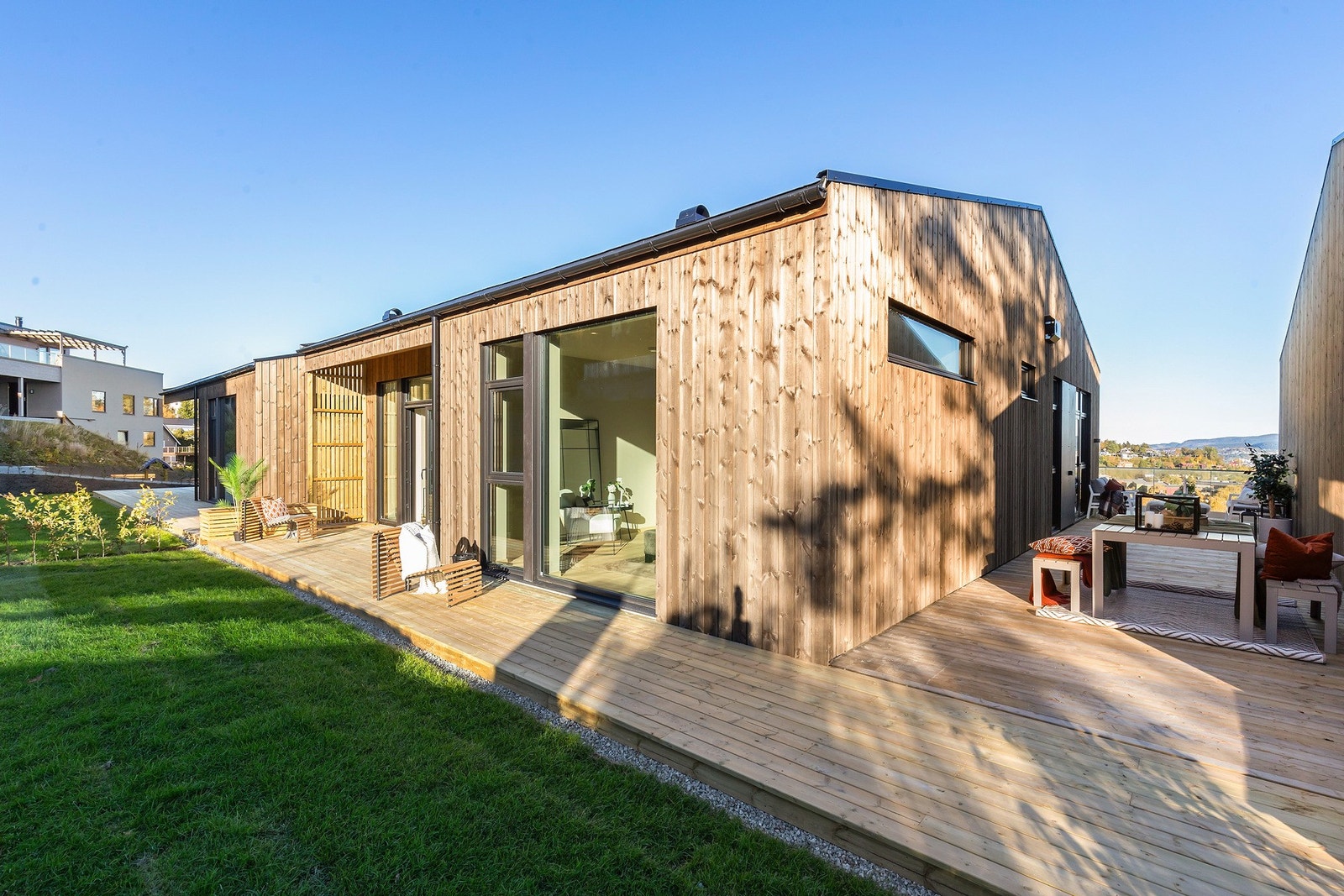 Terrassen strekker seg hele veien rundt boligen, på baksiden er det også nedgang til frodig plen. Galleribilde