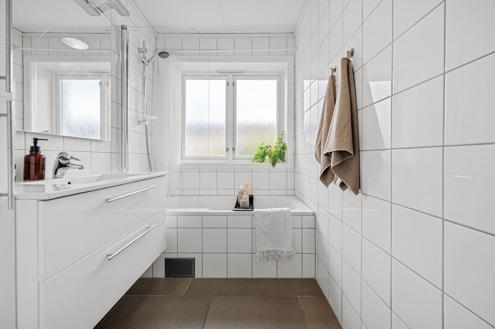 Det er badekar i enden av rommet og opplegg for vaskemaskin. Ekstra skap med oppbevaring på vegg. Galleribilde