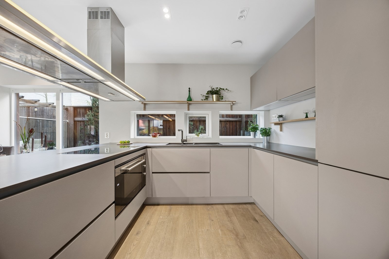 Kjøkkeninnredningen har elegante glatte fronter med moderne automatiske åpne- og lukkefunksjoner, toppet av en solid benkeplate i komposittstein. Galleribilde