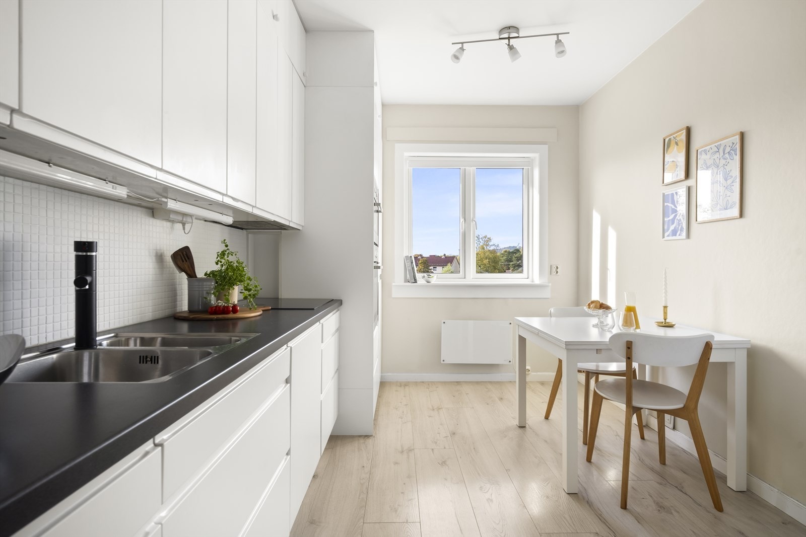 Moderne innredning med hvite, glatte fronter, fliser på veggen over kjøkkenbenken og benkeplate i laminat. Galleribilde