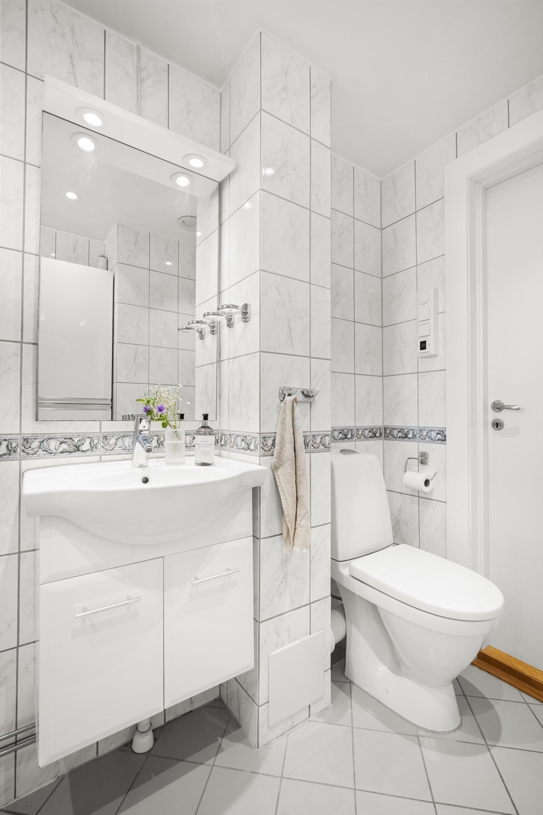 Badet er innredet med toalett, servant nedfelt i innredning og dusjhjørne (med forheng). Det er opplegg for vaskemaskin. Galleribilde