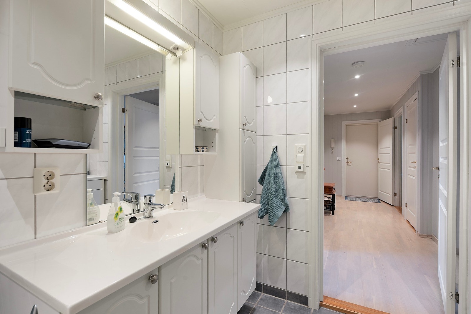 Helfliset bad med varmekabler i gulvet og god oppbevaringsplass i servantinnredningen Galleribilde