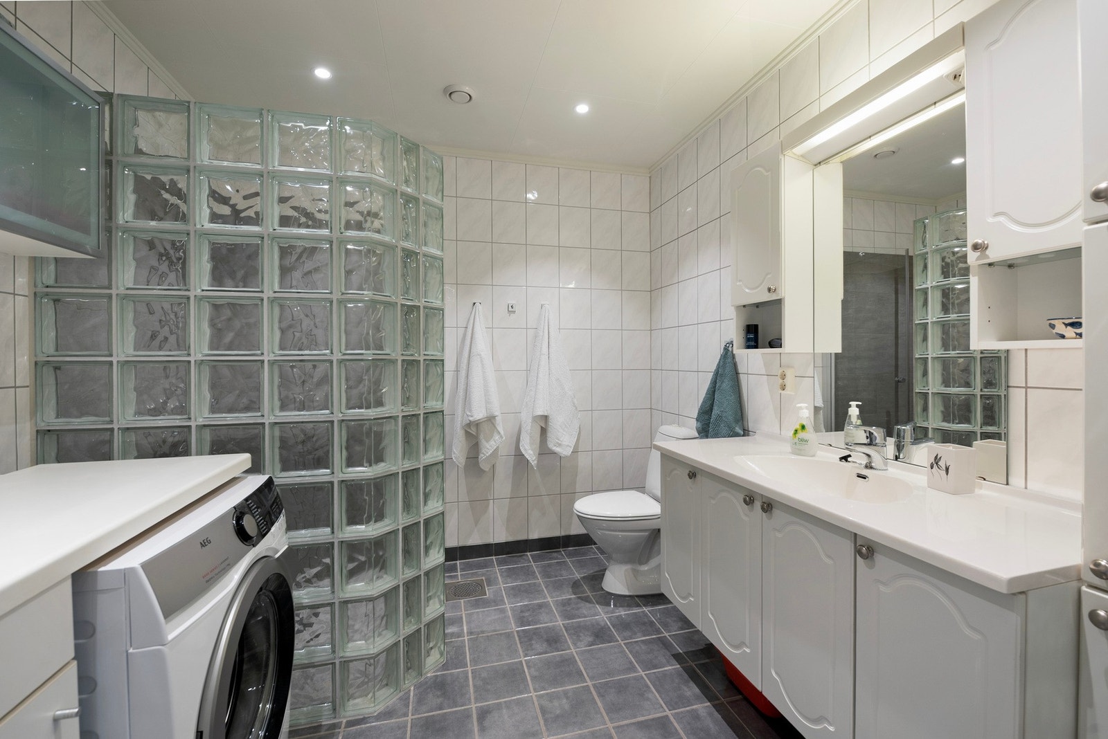 Her er det laget en praktisk ekstra benk for klesvask, og du har god plass til en romslig dusj i den tilpassede dusjnisjen Galleribilde