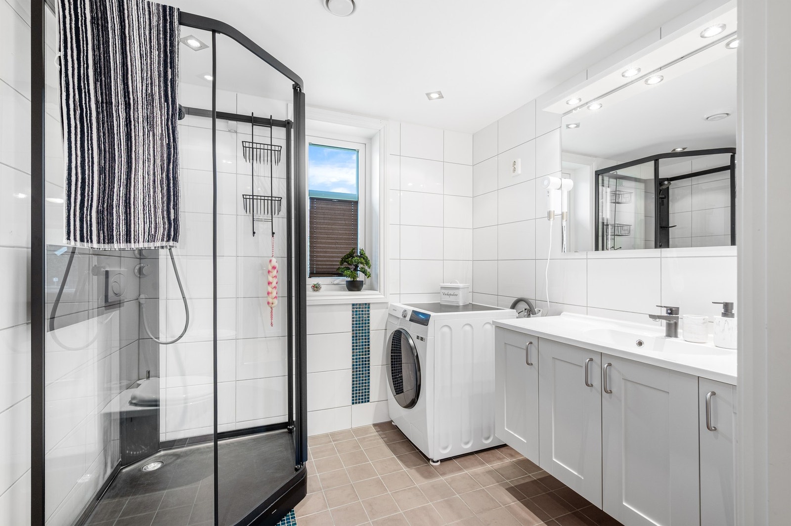 Lyst og romslig bad med opplegg for vaskemaskin. Badet har varme i gulv. Galleribilde