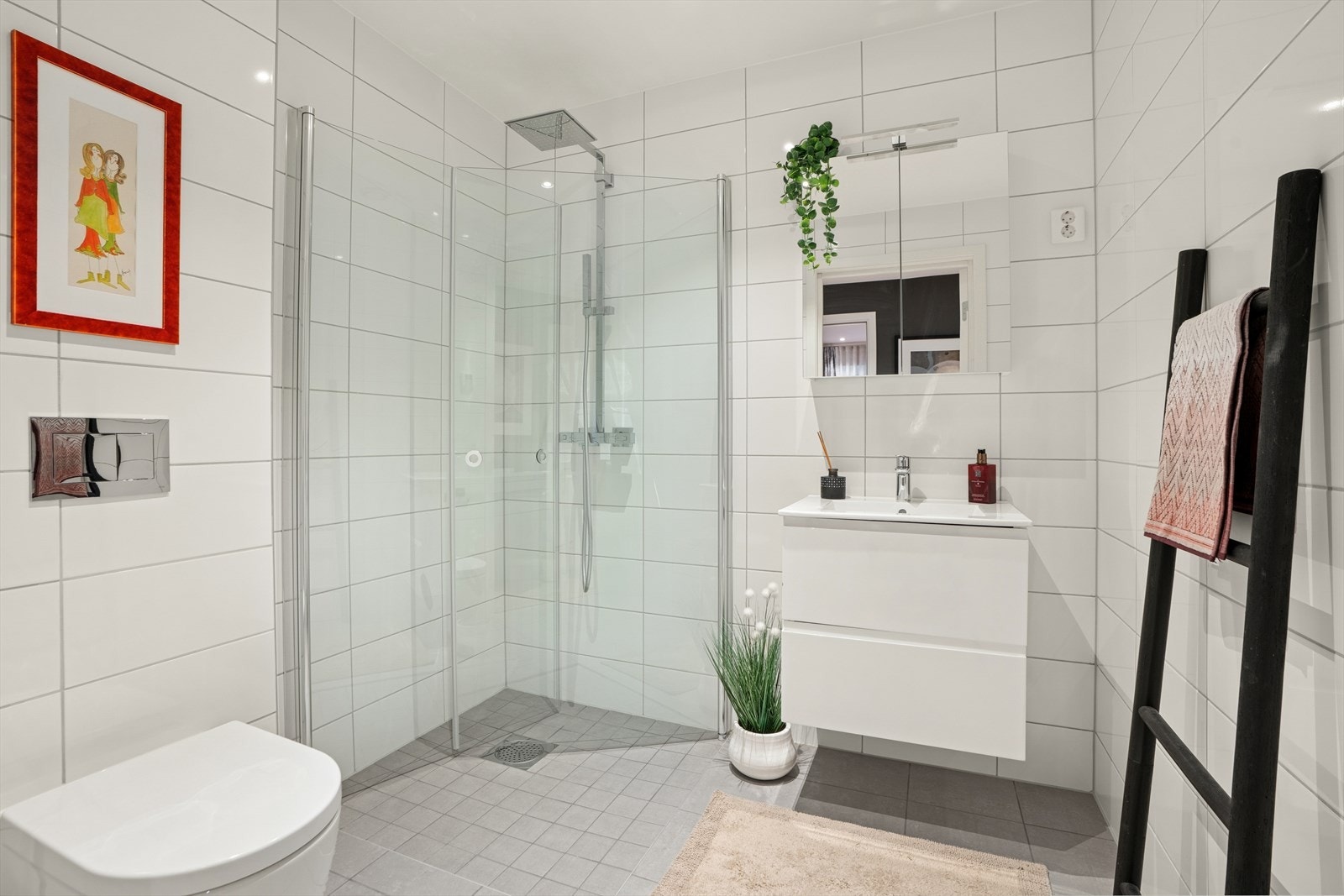 Badet er utstyrt med baderomsinnredning med servant og blandebatteri, speilskap, lys, dusjhjørne med glassdører og vegghengt toalett. Galleribilde