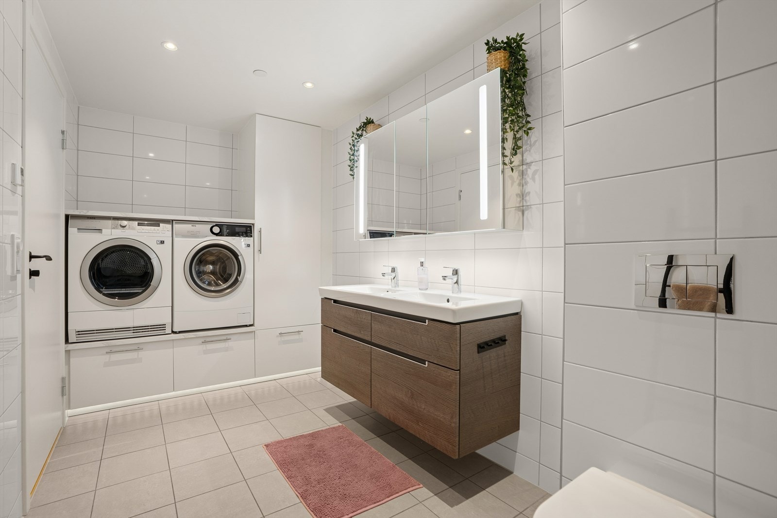 Rommet er utstyrt med baderomsinnredning med 2 servanter og blandebatteri, speilskap, lys, dusjhjørne med glassdører og vegghengt toalett. Innredningen er fra 2019. Det er opplegg for vaskemaskin. Galleribilde