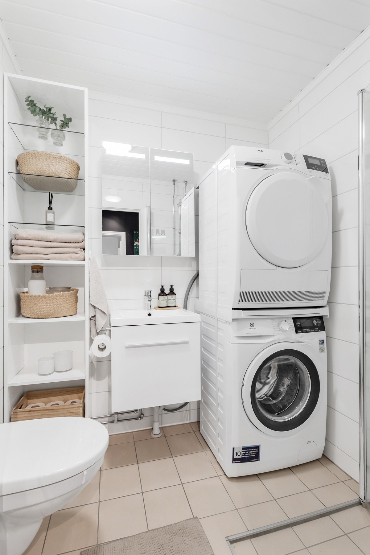 Rommet er utstyrt med vegghengt toalett, opplegg for vaskemaskin og innredning med nedsunket servant og speilskap Galleribilde