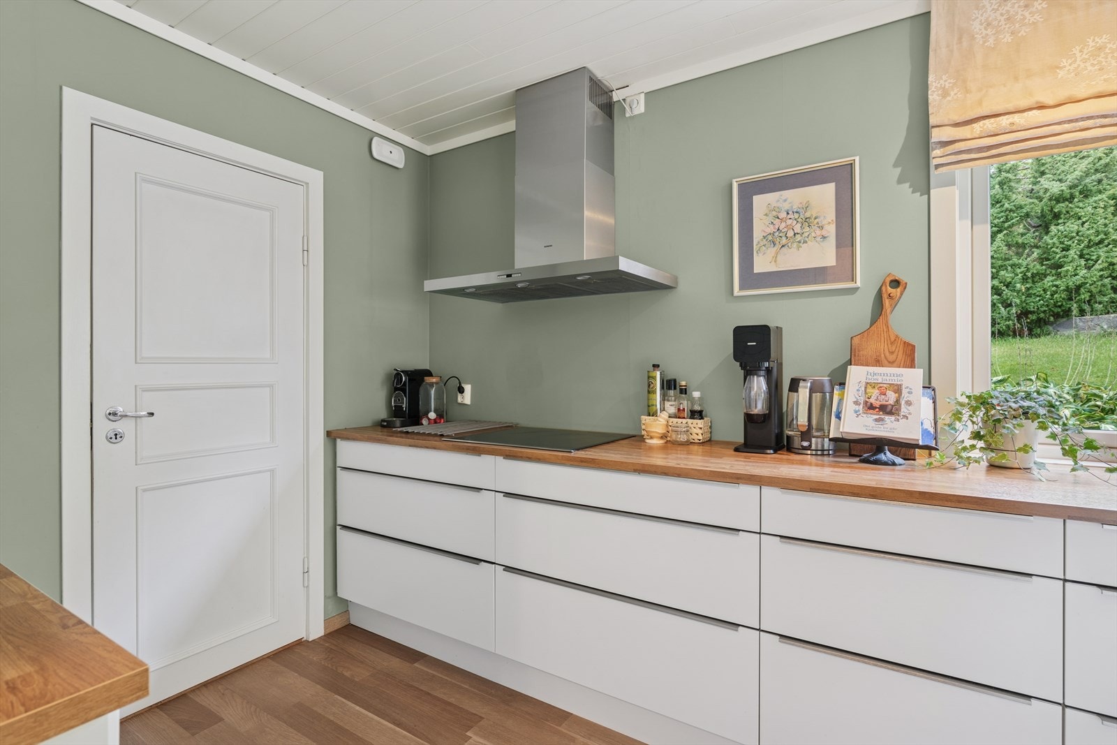 Kjøkkenet fremstår som stilrent og praktisk, med glatte fronter og heltre benkeplate som gir et tidløst uttrykk. Galleribilde