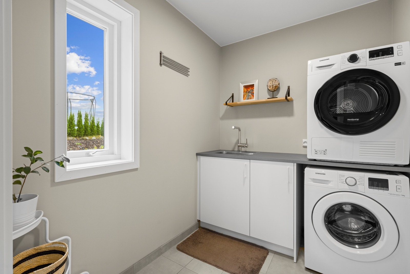 Praktisk vaskerom i første etasje med flislagt gulv, varmekabler, servant og opplegg for vaskemaskin. Et funksjonelt rom som forenkler hverdagen. Galleribilde