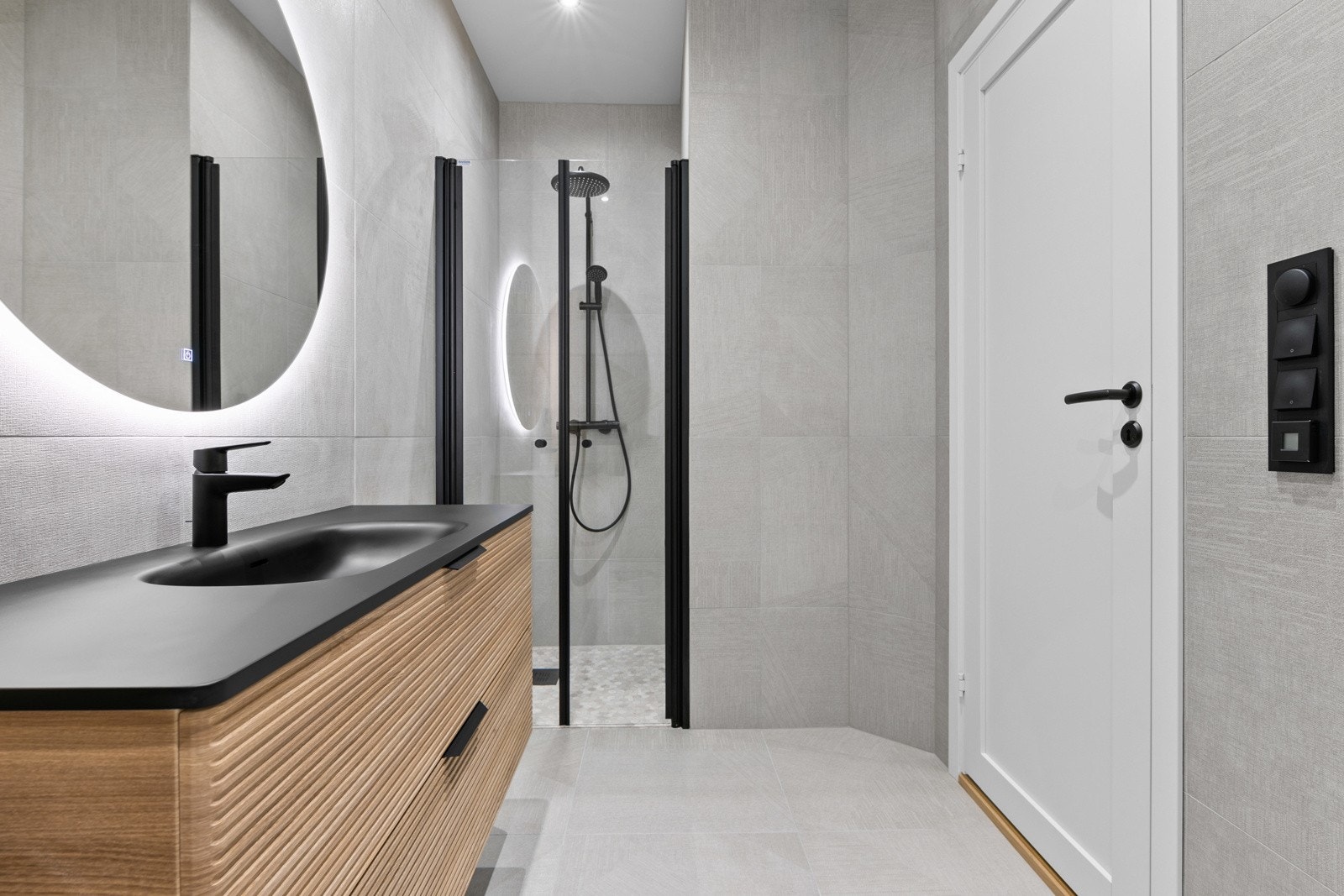 Det er dusjnisje med glassdør. Servant med innredning, toalett og speil med belysning Galleribilde