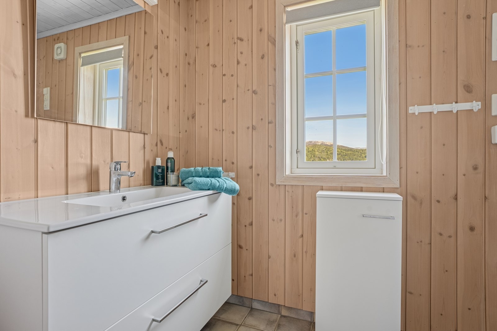 Badet har flislagt gulv med behagelig varme og veggene har panel og fliser i dussjonen Galleribilde