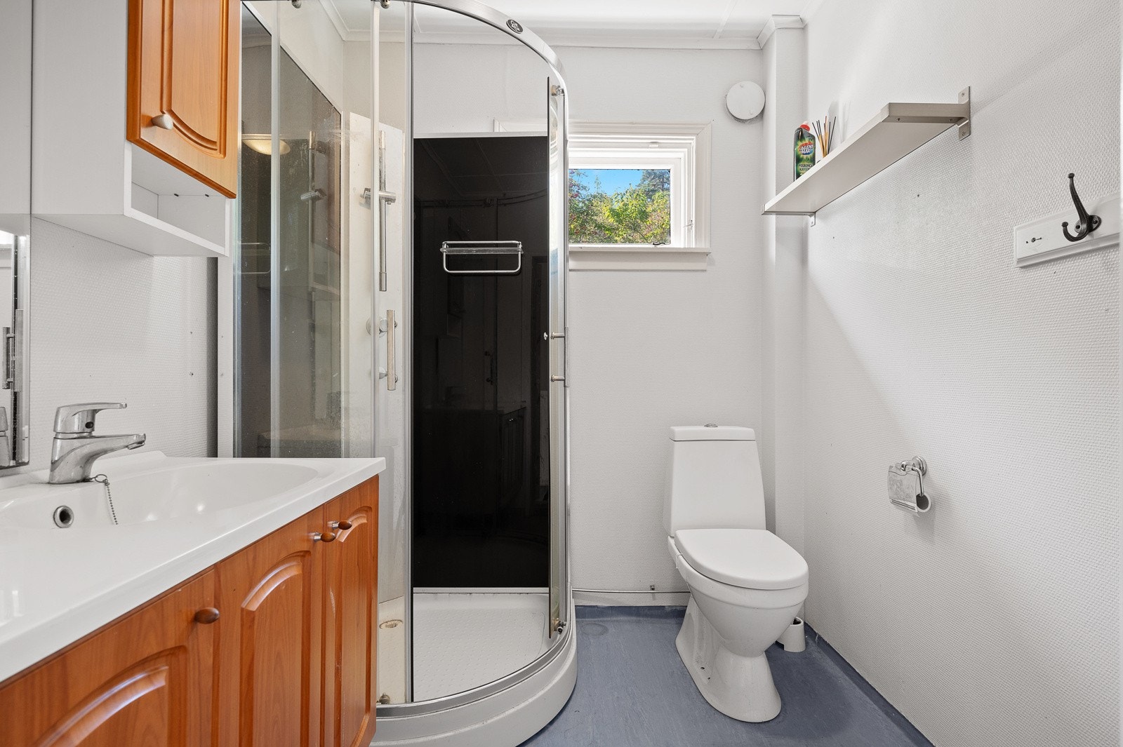 Bad med toalett, dusjkabinett og servant med skapinnredning. Galleribilde