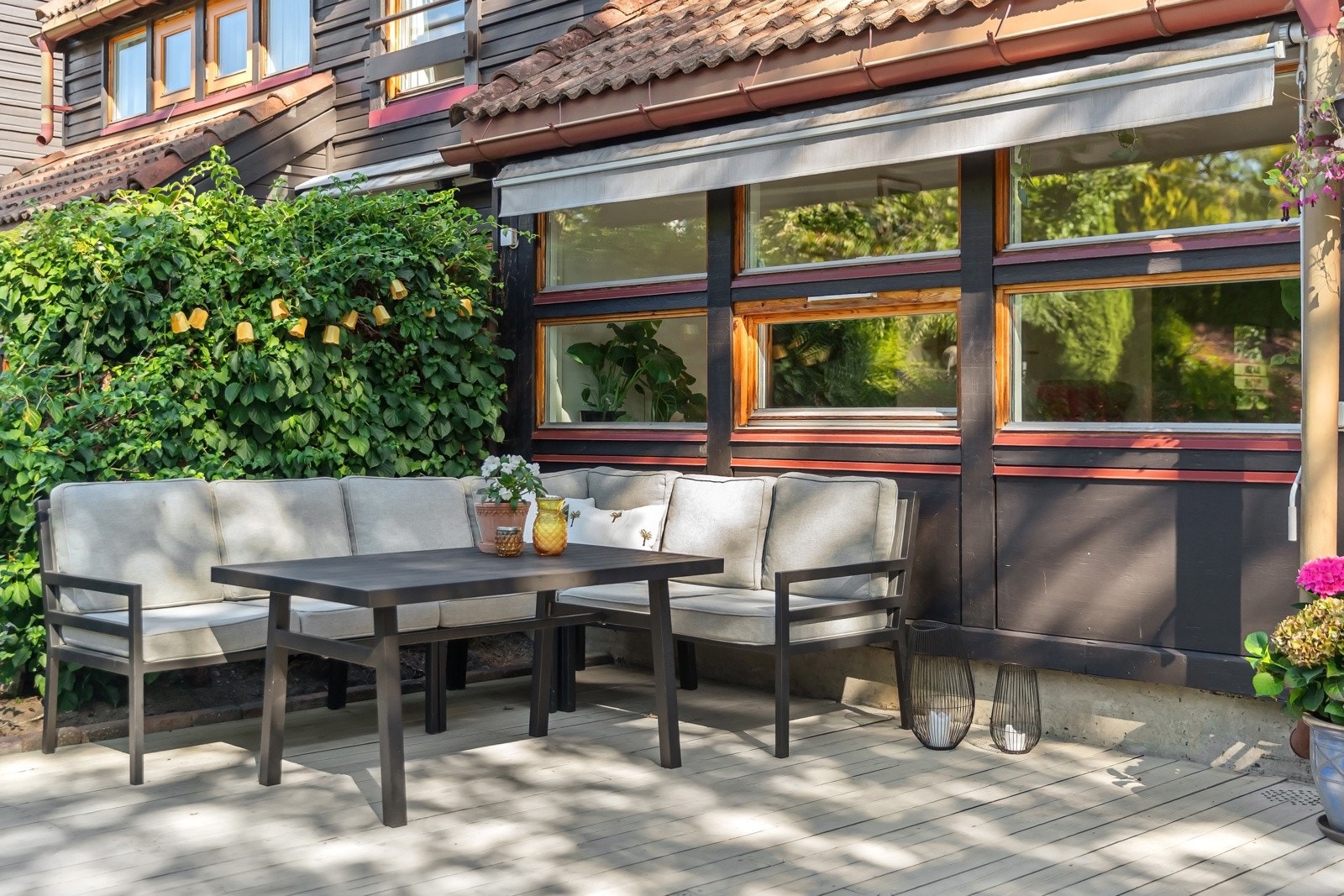 Uteplassen er utstyrt med markiser, plassbygd benk og har dekke av terrassebord. På sidene rammes den inn av rekkverk og frodig hekk. Galleribilde
