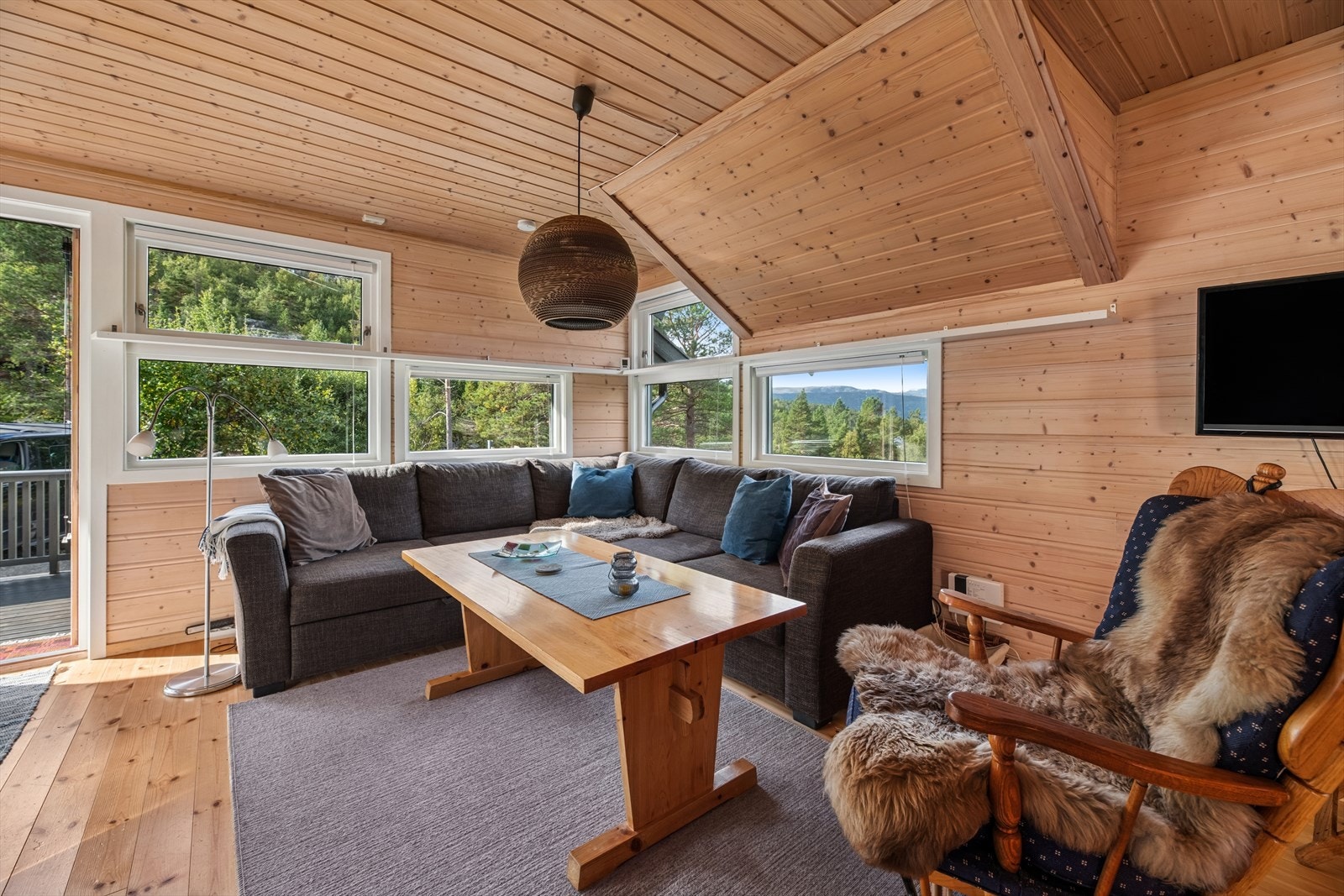 Gulvet er belagt med tregulv som gir en varm og naturlig følelse, mens veggene er kledd med trepanel som understreker den lune og atmosfæren i rommet. Galleribilde