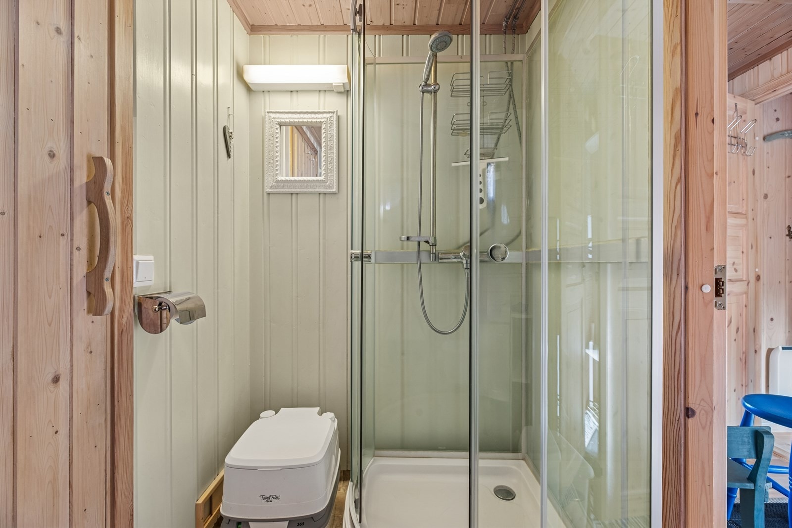 Badet har gulvbelegg i vinyl og vegger samt himling kledd med trepanel, noe som gir rommet et lunt preg. Rommet er innredet med servant nedfelt i skap, campingtoalett og dusjkabinett. Galleribilde