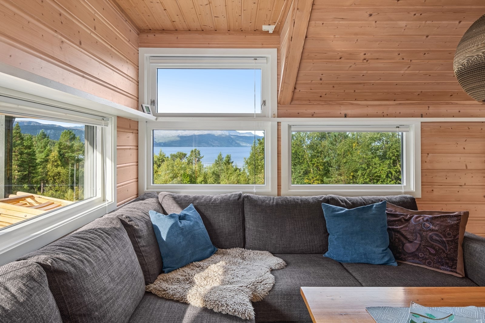 Sofagruppen er plassert ved vinduene, noe som gir rikelig med naturlig lys og en flott ramme rundt utsikten, perfekt for å nyte både dagslyset og landskapet utenfor. Galleribilde