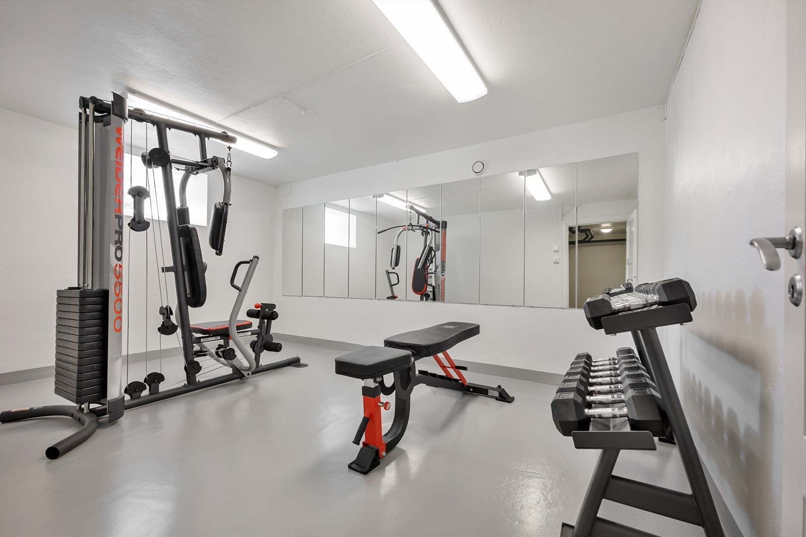 Opptatt av å holde deg i form? Her kan du gjøre det i eget hjem! De lyse malte overflatene bidrar til å forsterke romfølelsen, mens
speilene som er montert langs den ene veggen gir rommet en profesjonell treningsstudiofølelse. Galleribilde