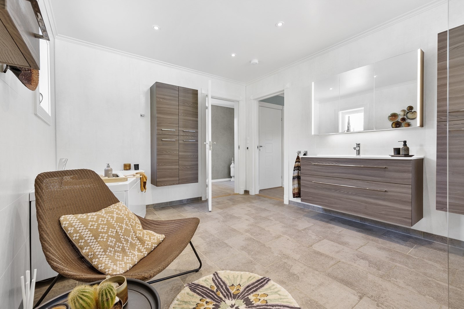 Badet er også utstyrt med en vegghengt wc og en elegant dansk servantinnredning med skuffer, overskap og flere sideskap, som gir rikelig med oppbevaringsplass. Galleribilde